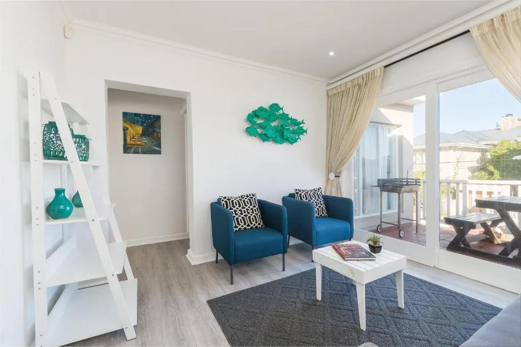 Modern lounge with blue armchairs, white shelving, and ocean view doors