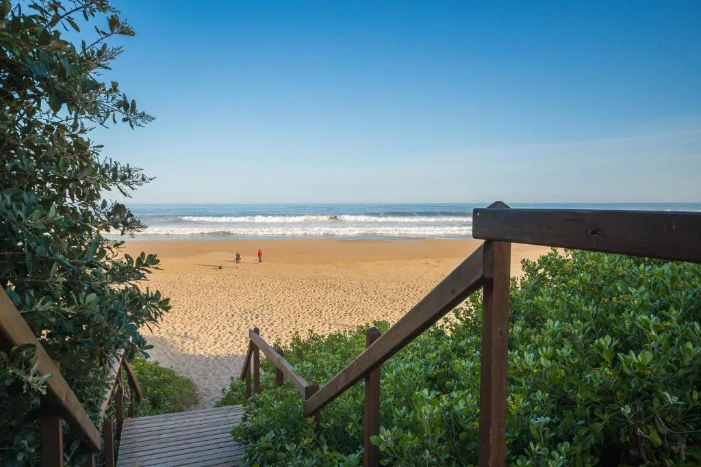 Beach access boardwalk with sandy shore and ocean waves ahead