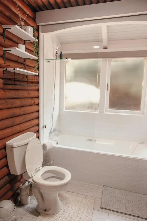 Clean bathroom with toilet, bathtub, shower enclosure, and wooden accent wall