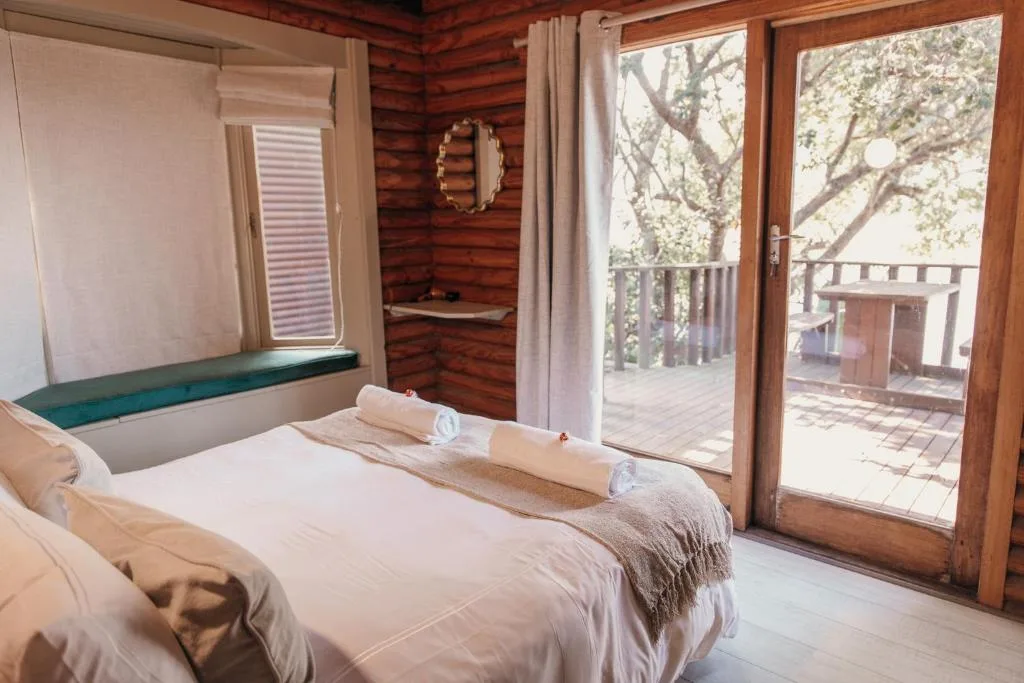 Spacious bedroom with queen bed, wooden walls, and glass doors opening to deck
