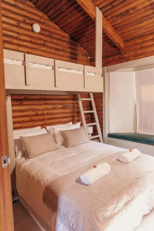Wooden cabin bedroom with bunk bed and rustic timber ceiling beams