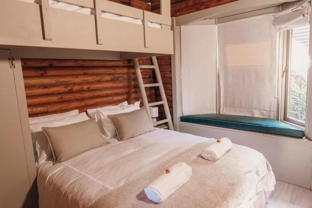 Bright bedroom with double bed, wooden headboard, loft bunk above, window seat