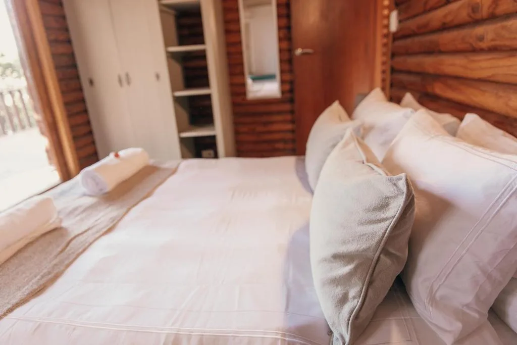 Spacious bedroom with crisp white bedding and wooden log cabin walls