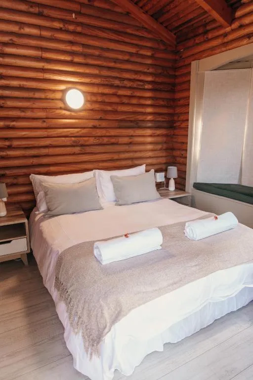Rustic log cabin bedroom with queen bed and white linens