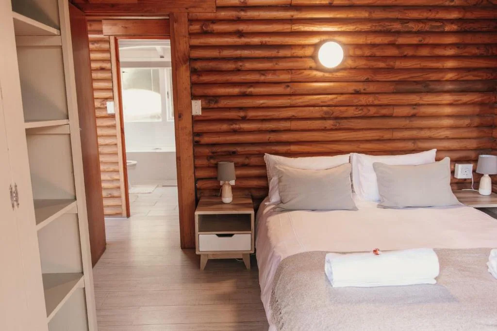 Cozy bedroom with log walls, queen bed, and en-suite bathroom entrance