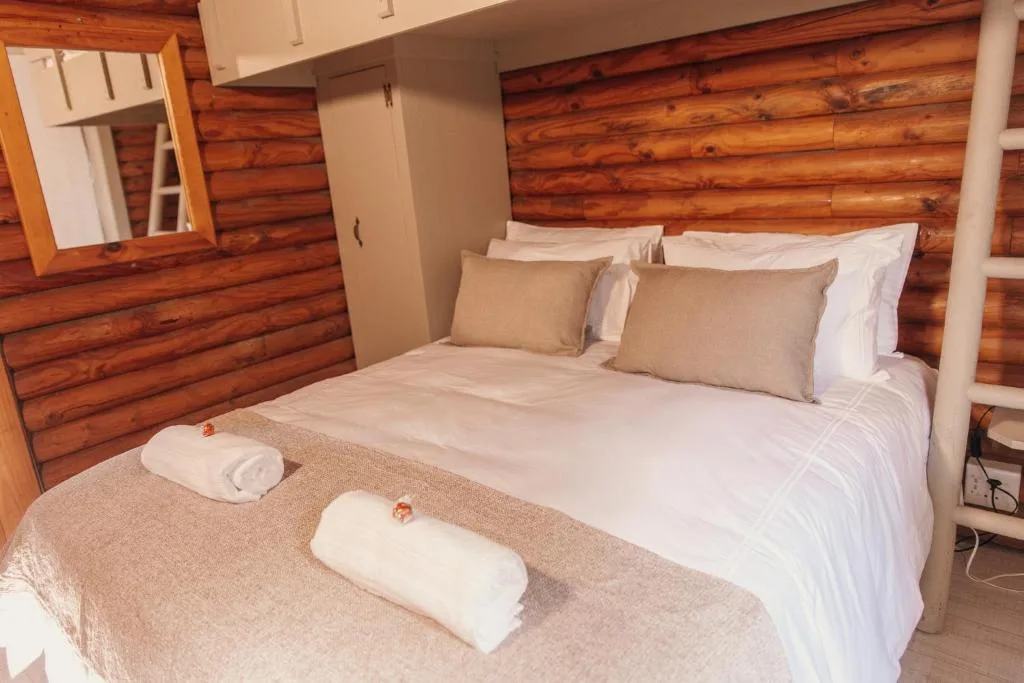 Cozy log cabin bedroom with queen bed, rustic wood walls, fresh linens