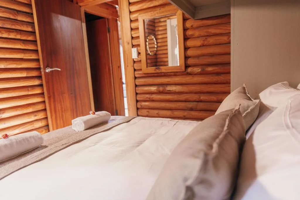 Cozy log cabin bedroom with white bedding and wooden interior walls