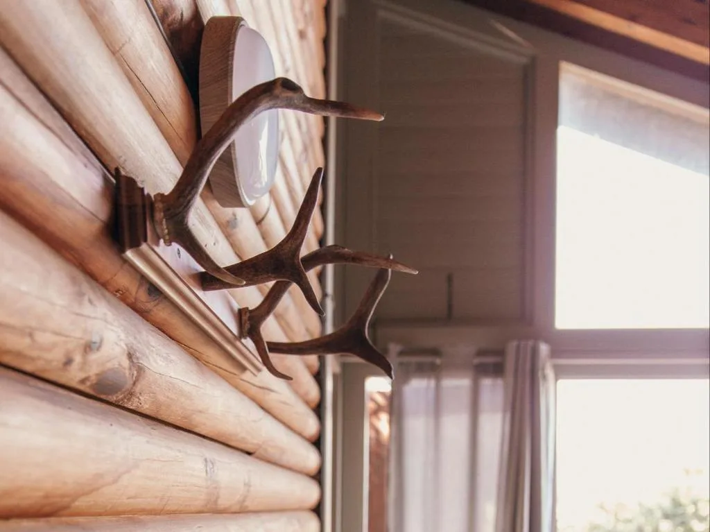 Decorative wooden antelope horns mounted on rustic log cabin wall
