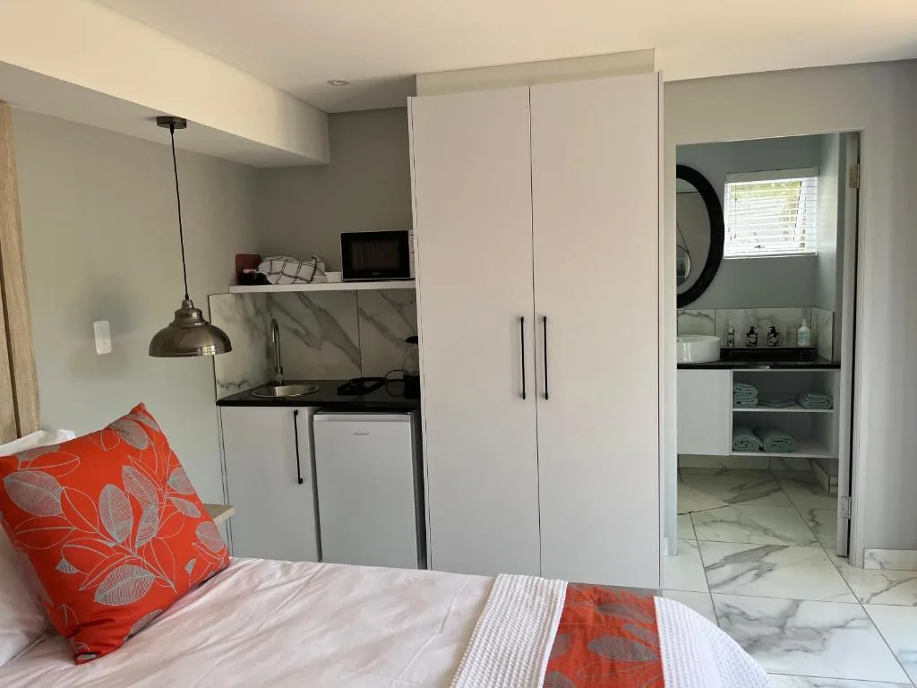 Modern bedroom with bed, kitchenette, wardrobe, and ensuite bathroom access