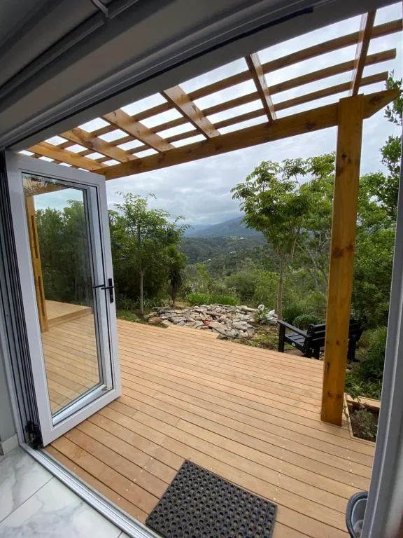 Wooden deck with pergola overlooking lush mountain valley landscape