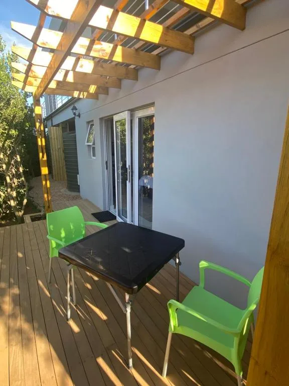 Wooden deck with black table and bright green chairs under pergola