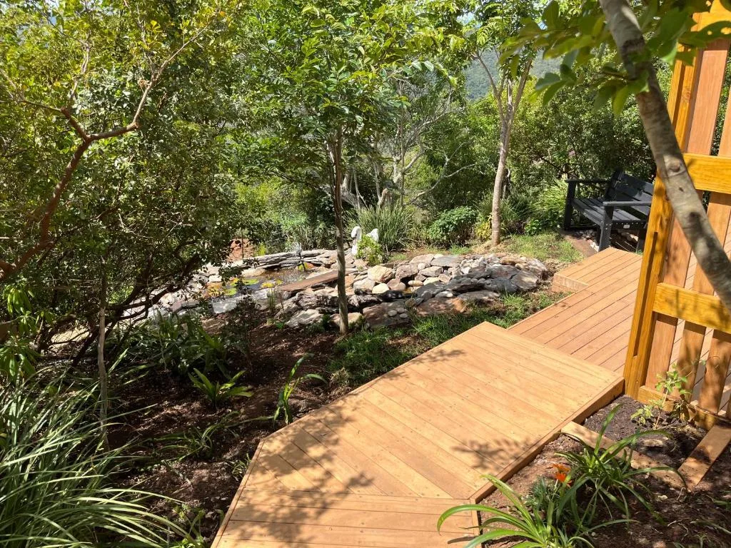Wooden deck with lush garden surroundings and native trees throughout