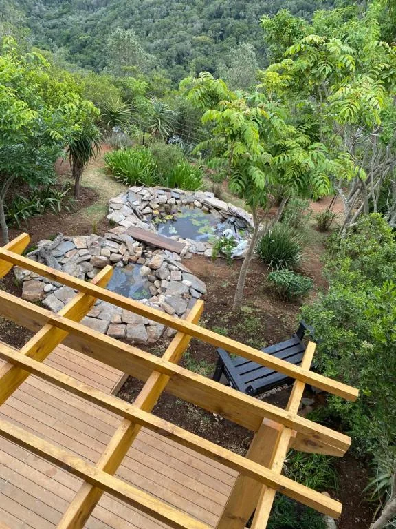 Wooden deck overlooking garden with natural stone pond and lush vegetation
