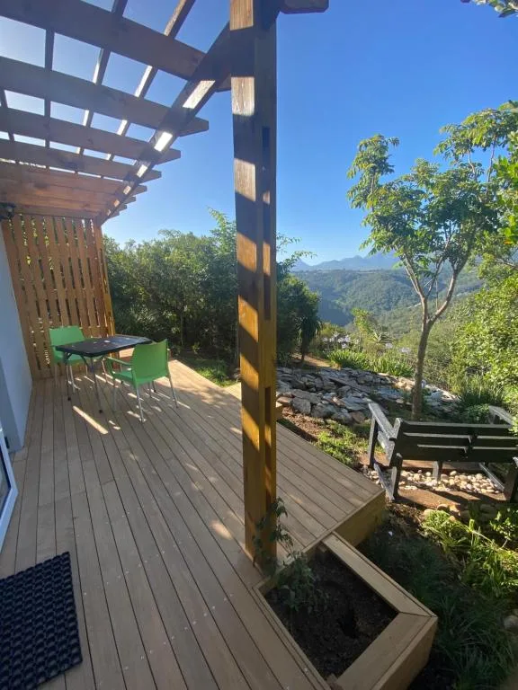 Wooden deck with pergola, green chairs, and mountain valley views