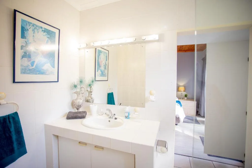 Modern bathroom with white vanity, round sink, and large illuminated mirror