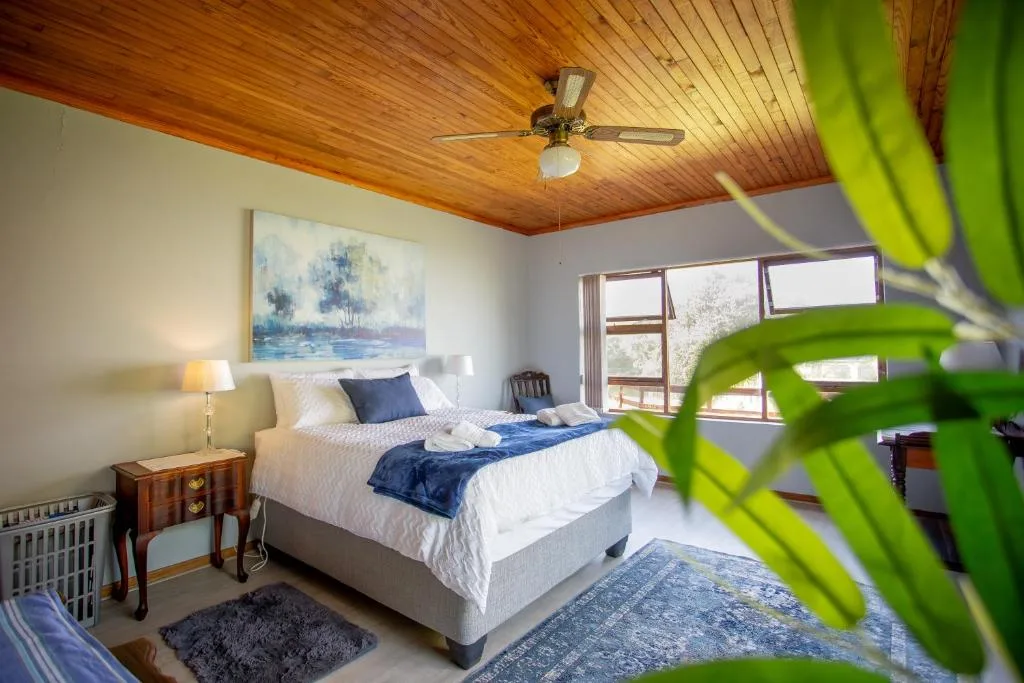 Bright bedroom with queen bed, wooden ceiling, and potted plant accent