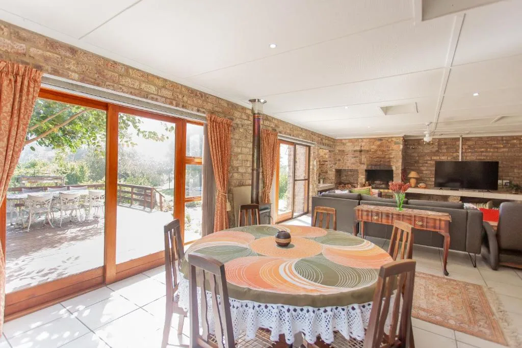 Dining area with round table and wooden chairs, opening to deck view