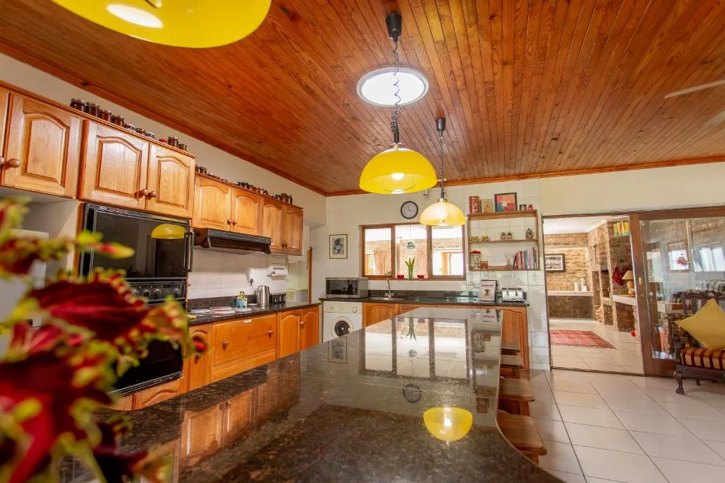 Spacious kitchen with wooden cabinetry, granite countertop, yellow pendant lights