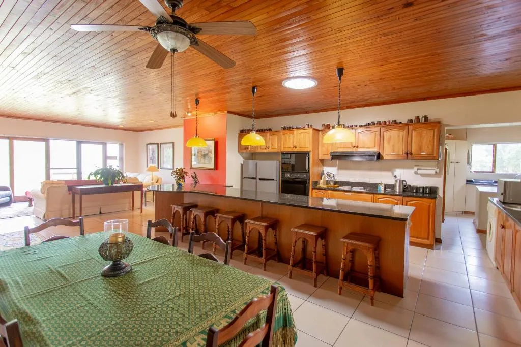 Open-plan kitchen with wooden cabinetry, island seating, and stainless steel appliances