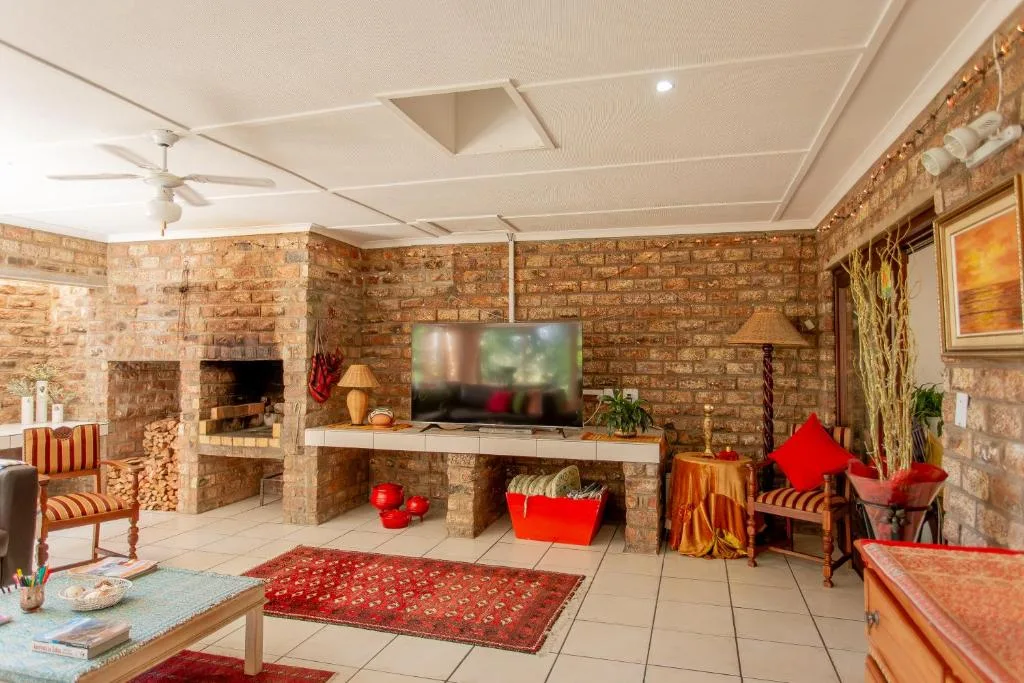 Spacious lounge with fireplace, brick walls, and flat-screen television