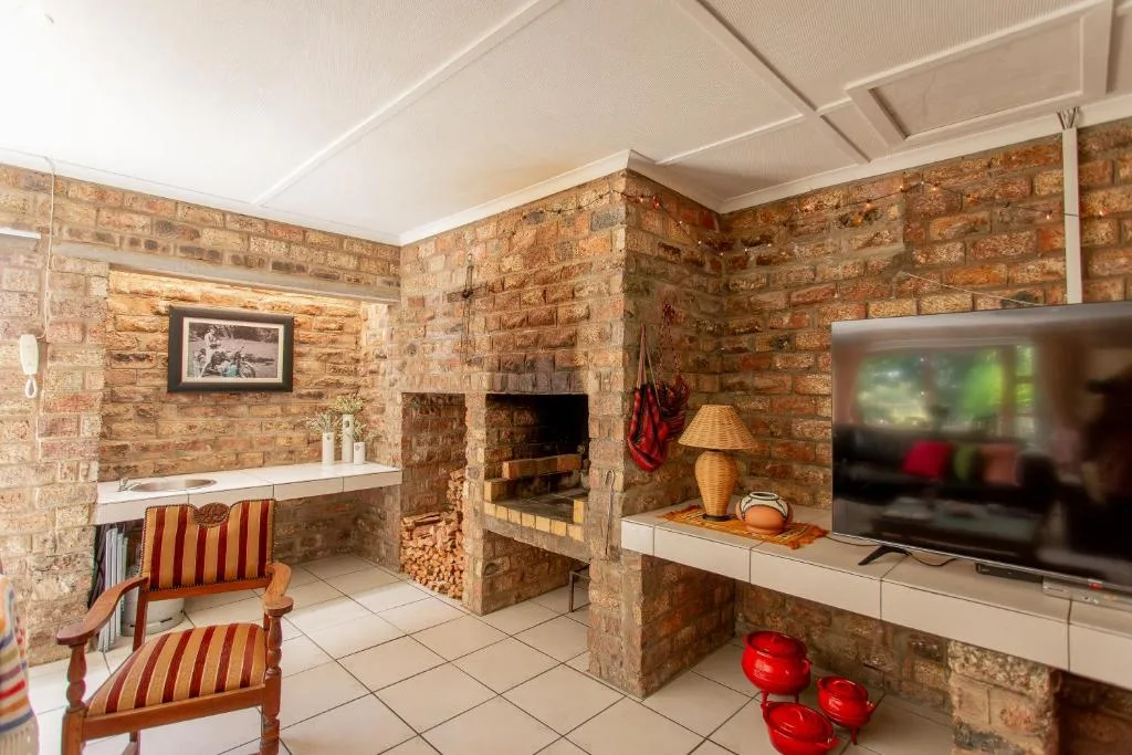 Brick lounge with fireplace, TV, and striped armchair seating
