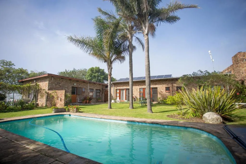 Sparkling swimming pool with brick property and palm trees behind