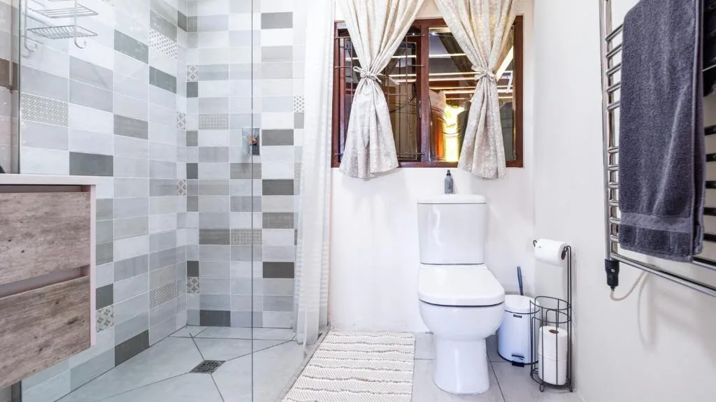 Modern bathroom with patterned tile shower, toilet, sink, and towel rail