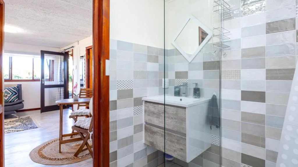 Modern bathroom with patterned tile walls, vanity sink, and glass shower enclosure