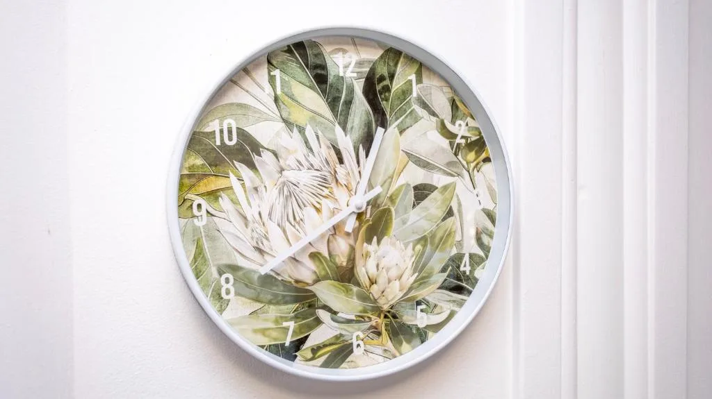 Decorative wall clock with botanical protea flower design and foliage