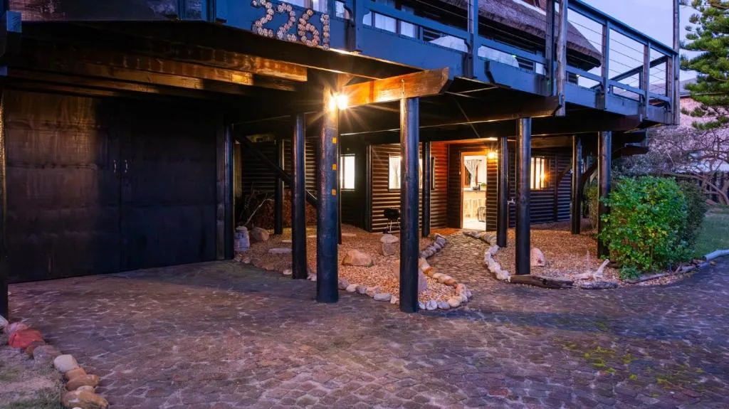 Modern home entrance with covered carport, wooden siding, and ambient lighting