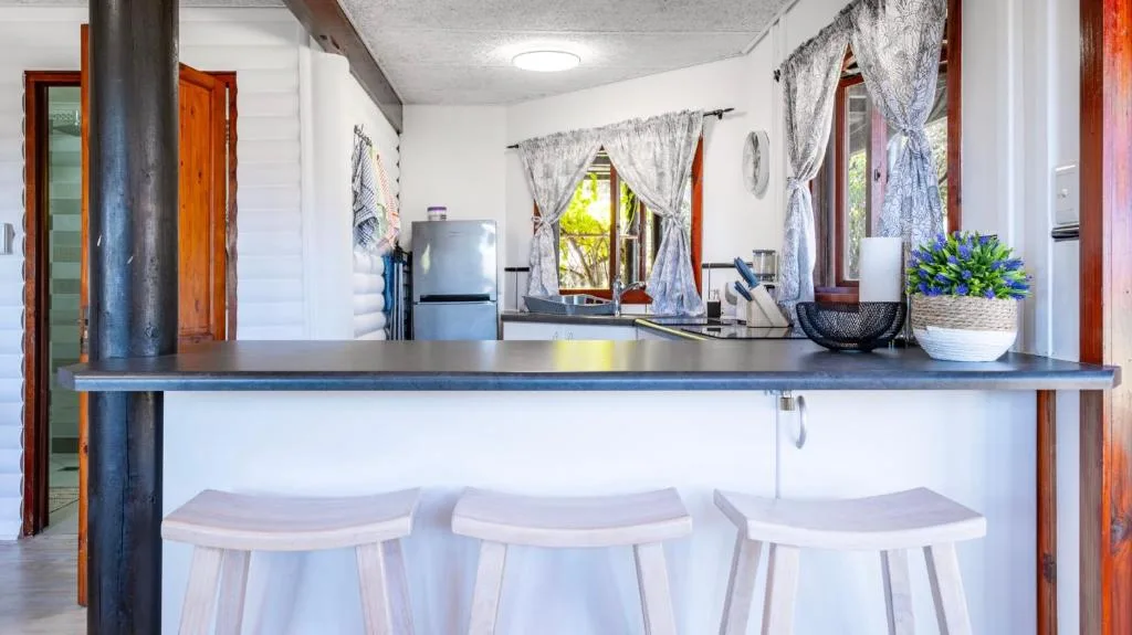 Modern kitchen with island counter, bar stools, stainless steel appliances, and natural light
