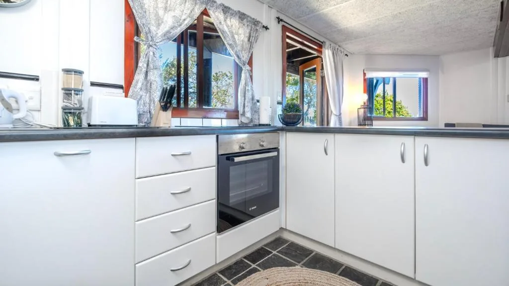 Bright modern kitchen with white cabinetry, black countertop, and garden views