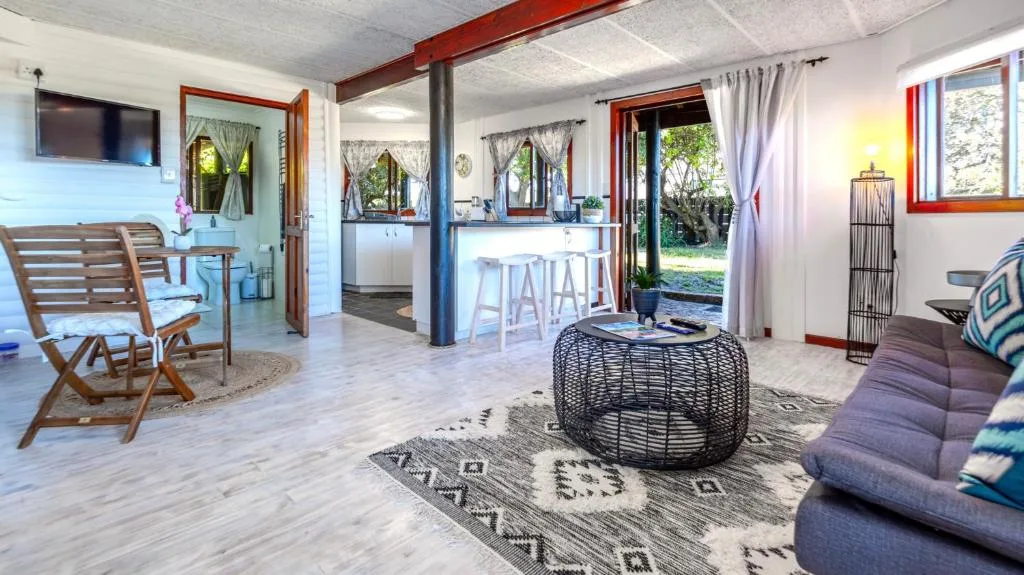 Spacious open-plan lounge with sofa, woven poufs, and garden views