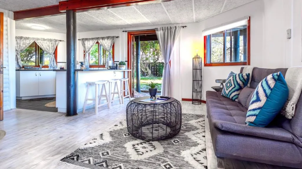 Open-plan lounge with gray sofa, geometric patterned rug, and garden views