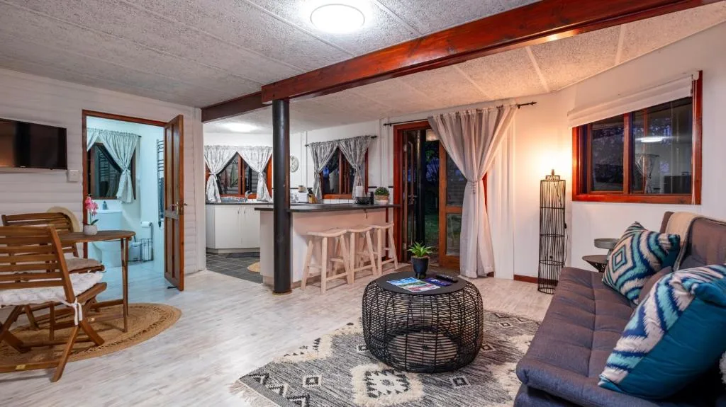 Open-plan lounge with sofa, woven ottoman, and wooden chair seating