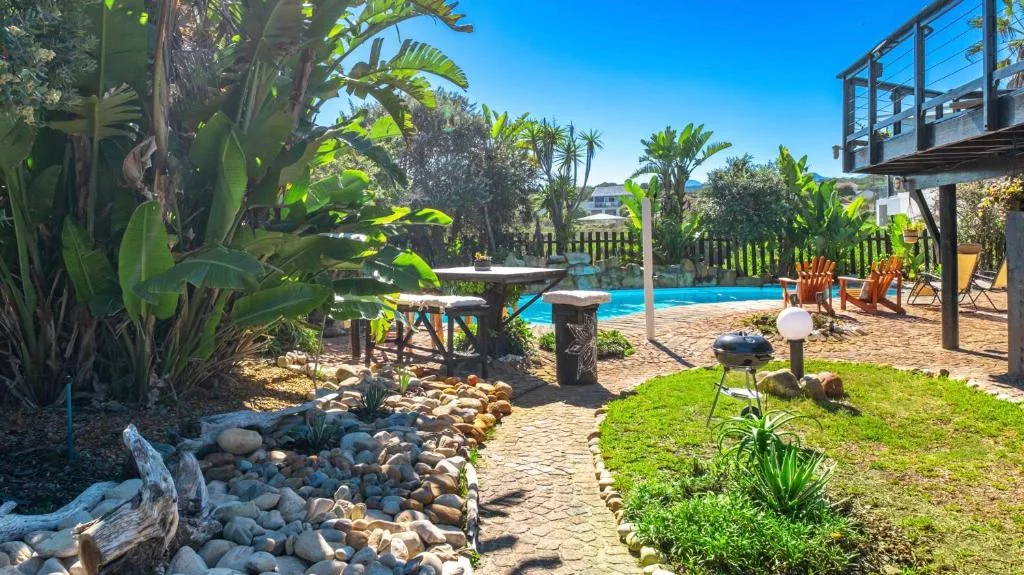 Swimming pool with tropical landscaping, braai area, and patio seating