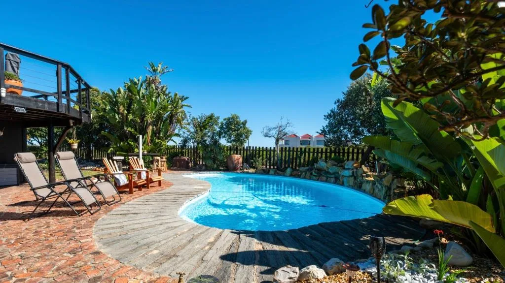 Sparkling blue swimming pool with wooden deck and lounge chairs