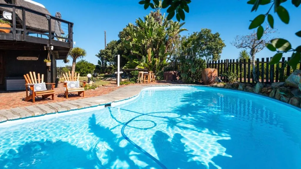 Bright blue swimming pool with lounge chairs and garden views
