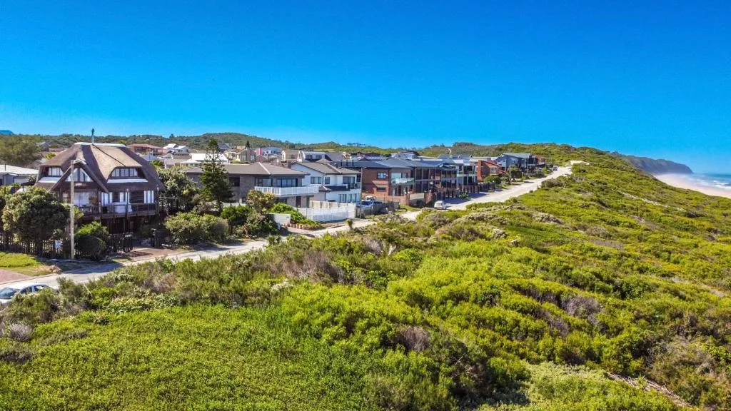 Coastal village nestled among lush green hills with ocean and beach visible