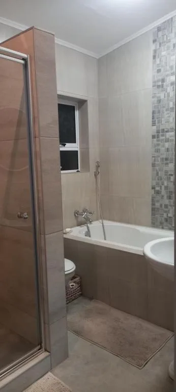 Modern bathroom with shower cubicle, bathtub, and tile accents