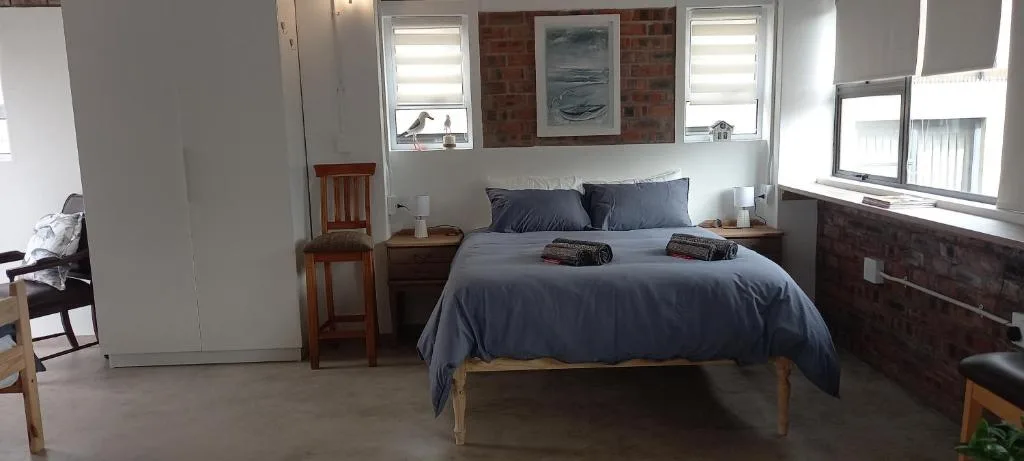 Bedroom with blue bedding, wooden furniture, and brick accent wall