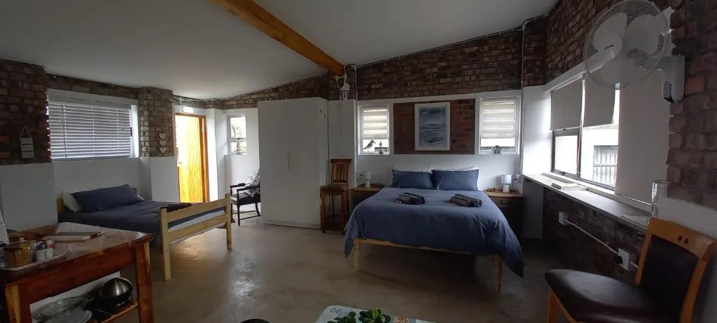 Spacious bedroom with double bed, exposed brick walls, and natural light