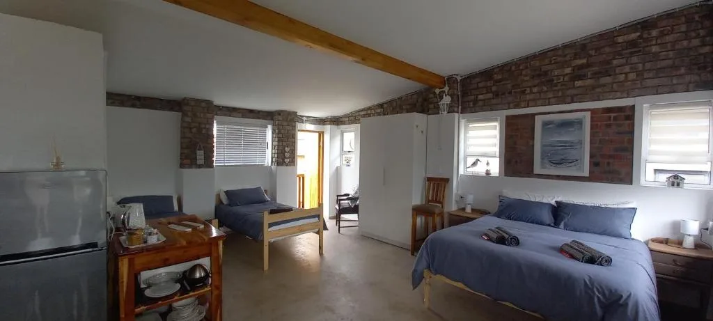 Spacious bedroom with double bed, blue bedding, wooden furniture, and brick accents