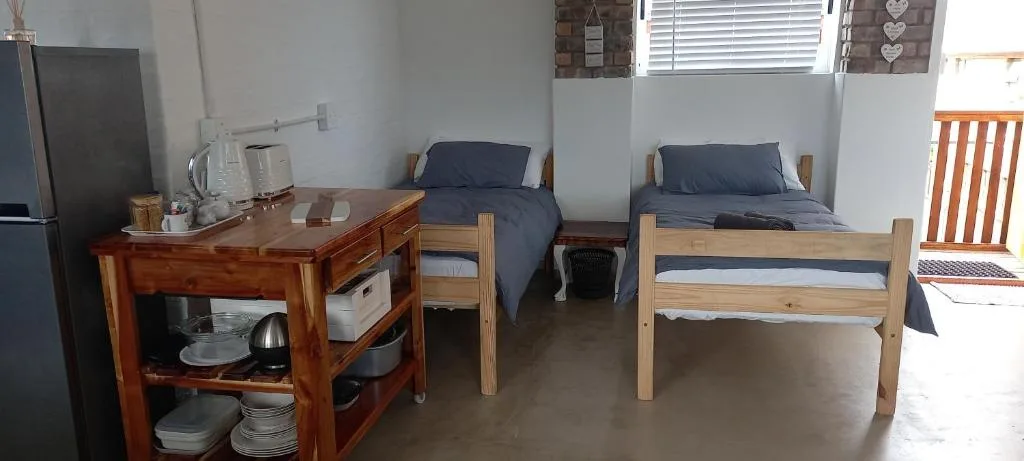 Twin bedroom with wooden beds and navy bedding, kitchenette visible