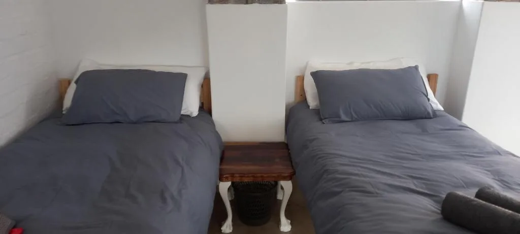 Twin beds with dark gray bedding and wooden headboards in bright room