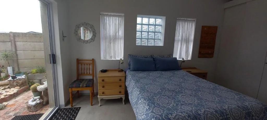 Spacious bedroom with queen bed, wooden dresser, and garden access doors