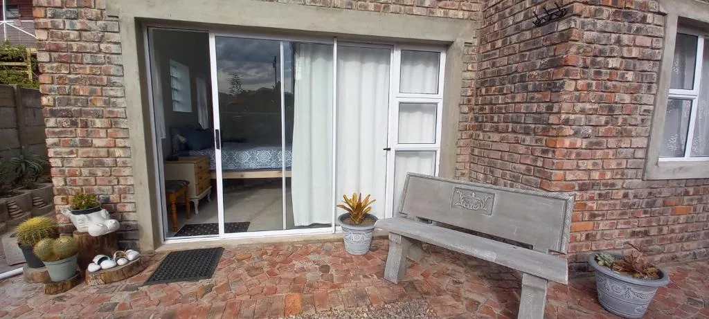 Brick patio with bench seating and potted plants near glass doors