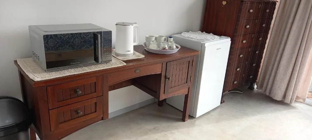 In-room kitchenette with microwave, kettle, mini fridge, and wooden desk
