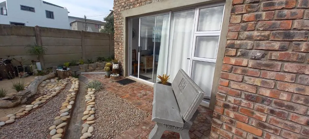 Brick cottage exterior with patio, sliding doors, and decorative pebble garden