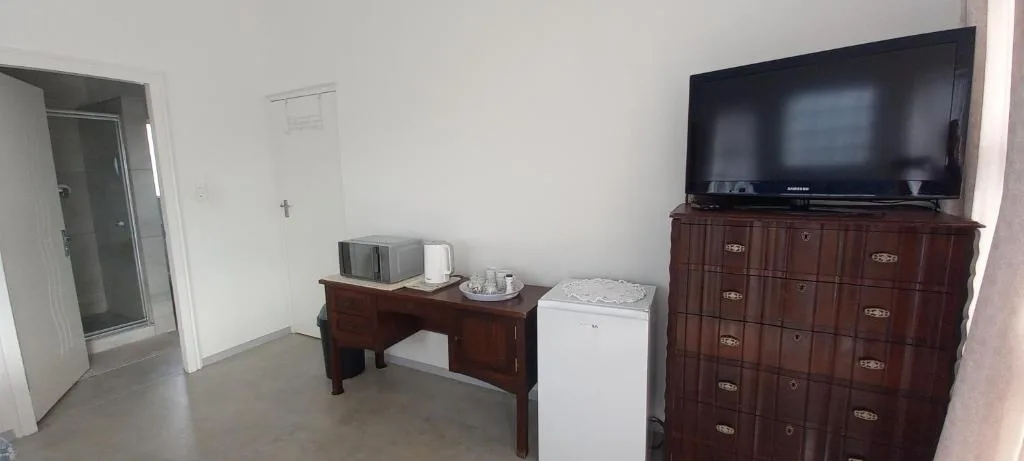Lounge area with flat-screen TV mounted above wooden dresser and seating furniture